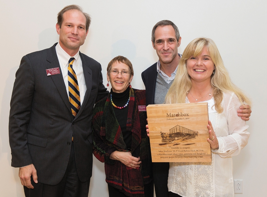 Two men and two women smile and hold a plaque.  